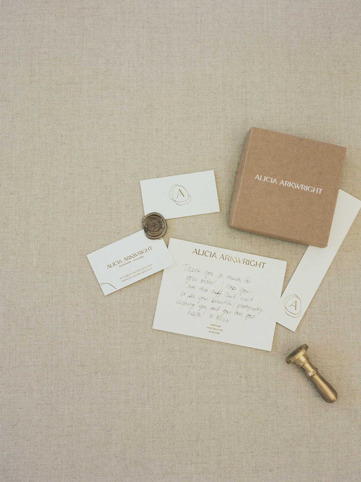 flatlay with beige linen, business cards, wax seal, branded details, designer brand photos