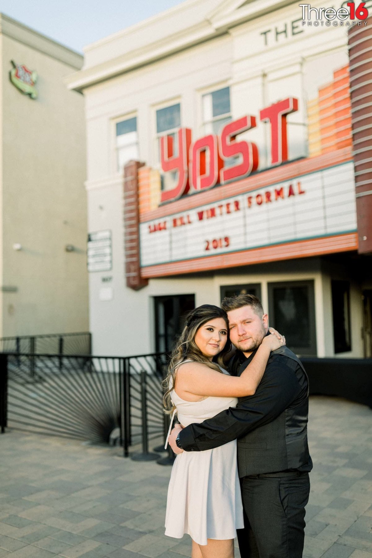 Engaged couple embrace in front of the Yost Theater in Santa Ana