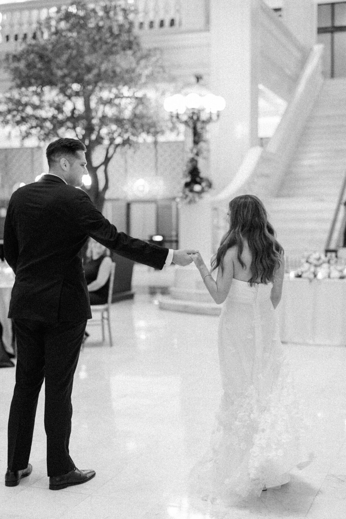 A romantic black and white wedding photo of a newlywed couple sharing their first dance at The Exchange, surrounded by candlelight and elegant decor.