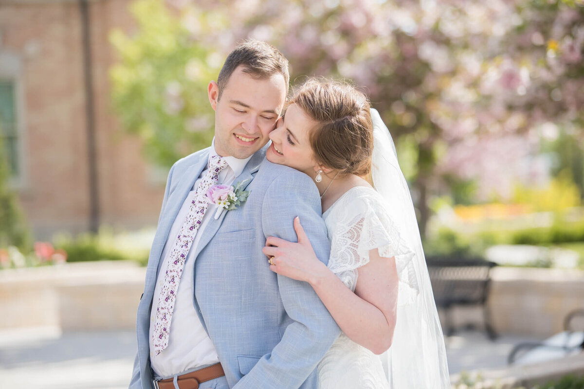 a bride leaning over shoulder of a man in a blue suit