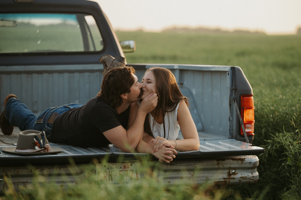 Image of Alberta engaged couple kissing in the truck bed 