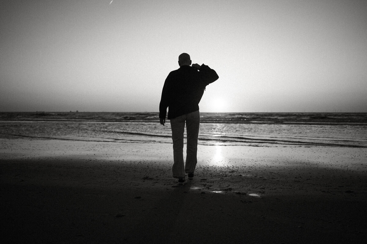 Vrouw loopt op het strand en kijkt naar zonsondergang