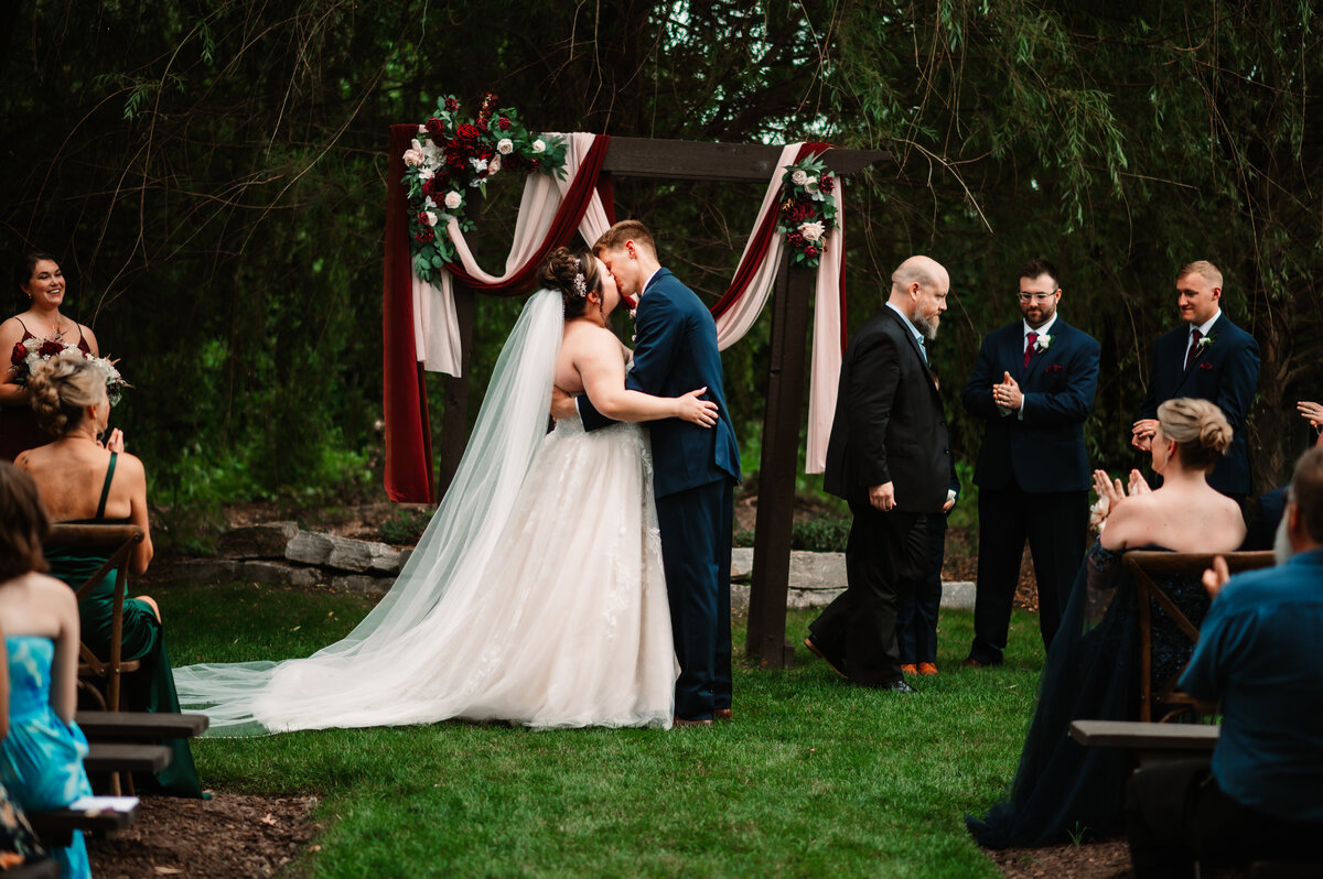 NEwlyweds kiss in the lawn to end their outdoor ceremony