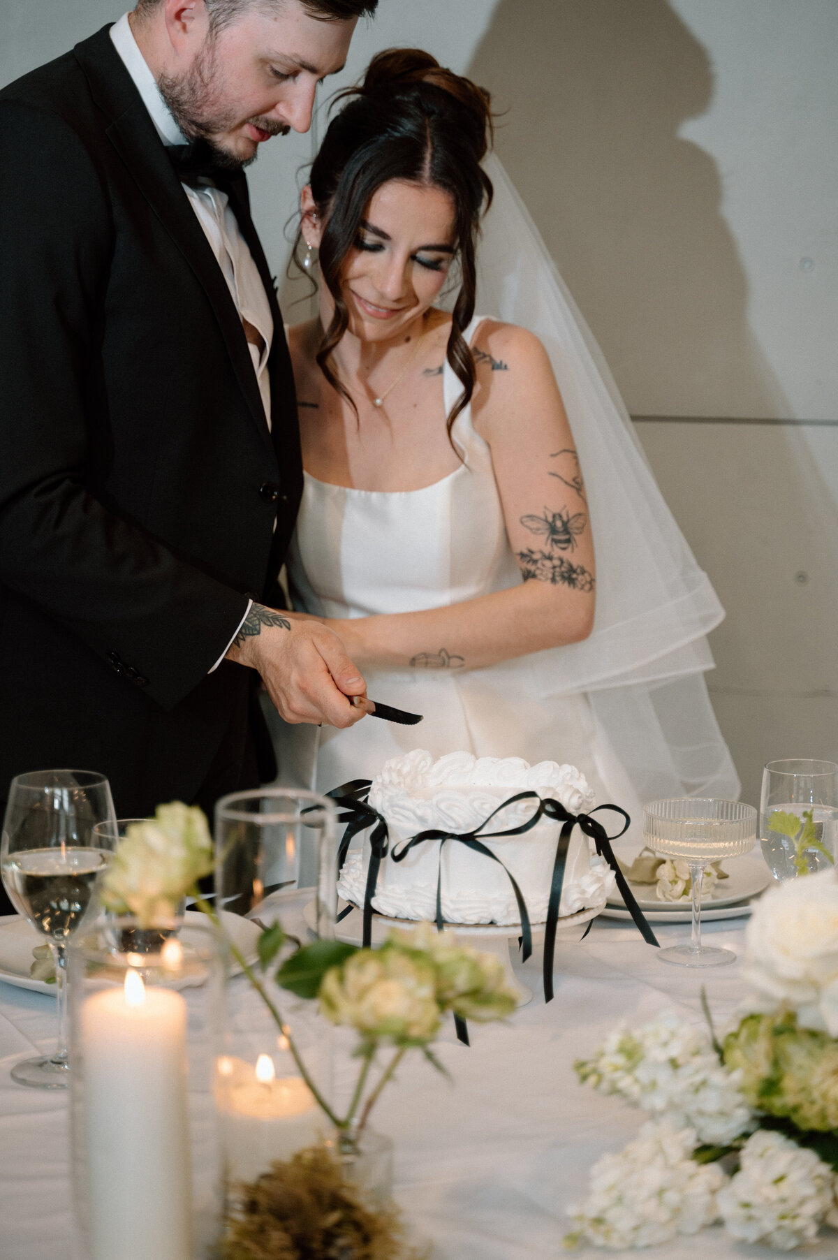 Bride smiles while cutting cake with groom during their documentary-style reception.