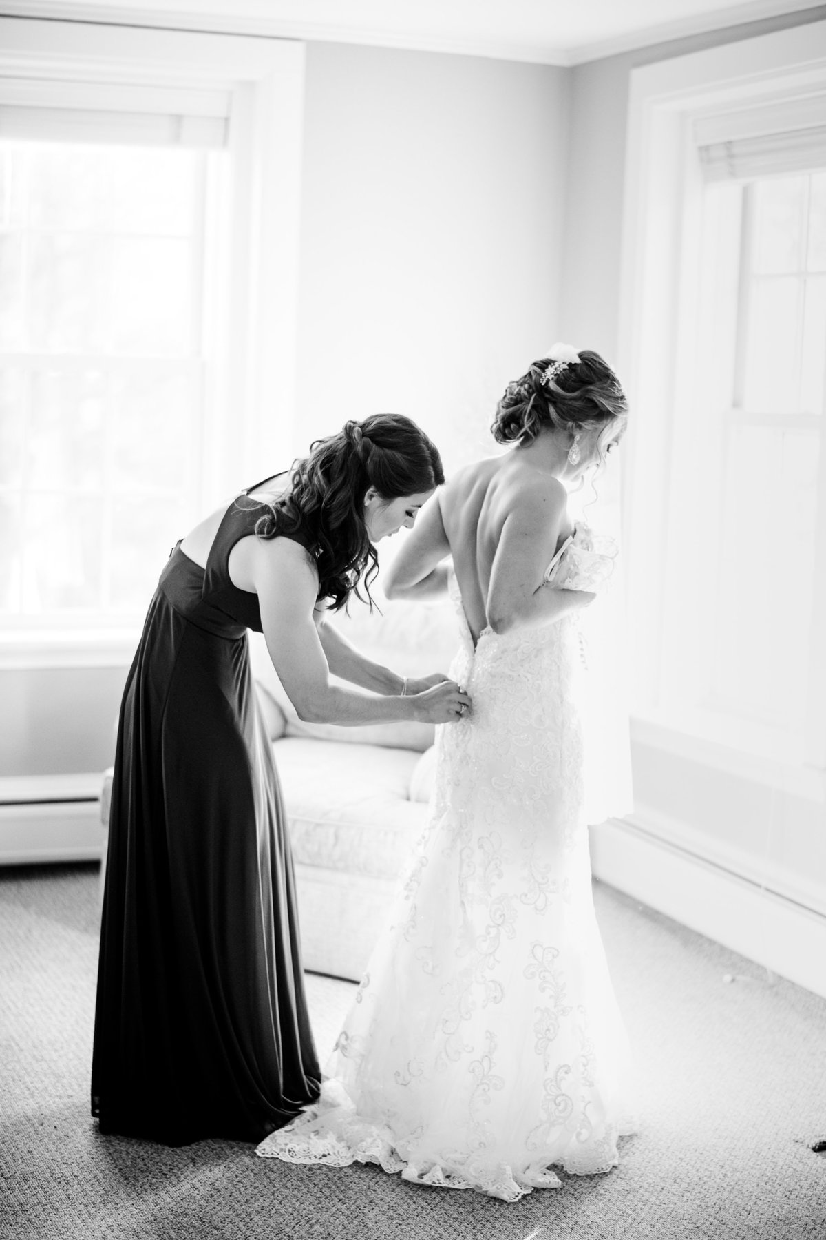 bride putting on her wedding gown black and white image