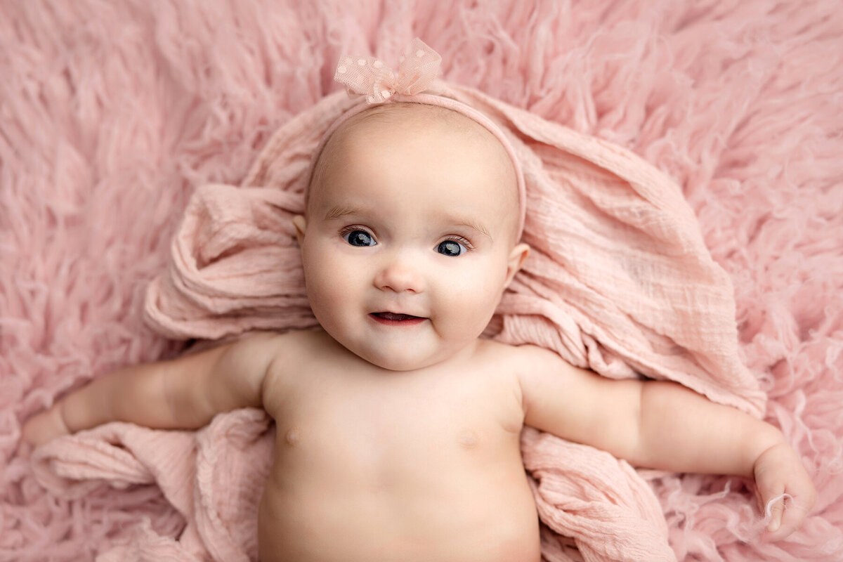 Baby girl laying on pink rug