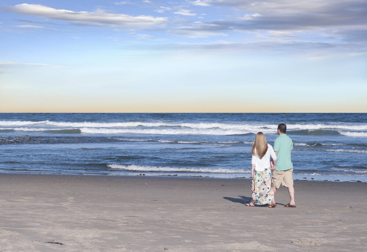 Engaged couple holding hands walking the beach in engagement photos
