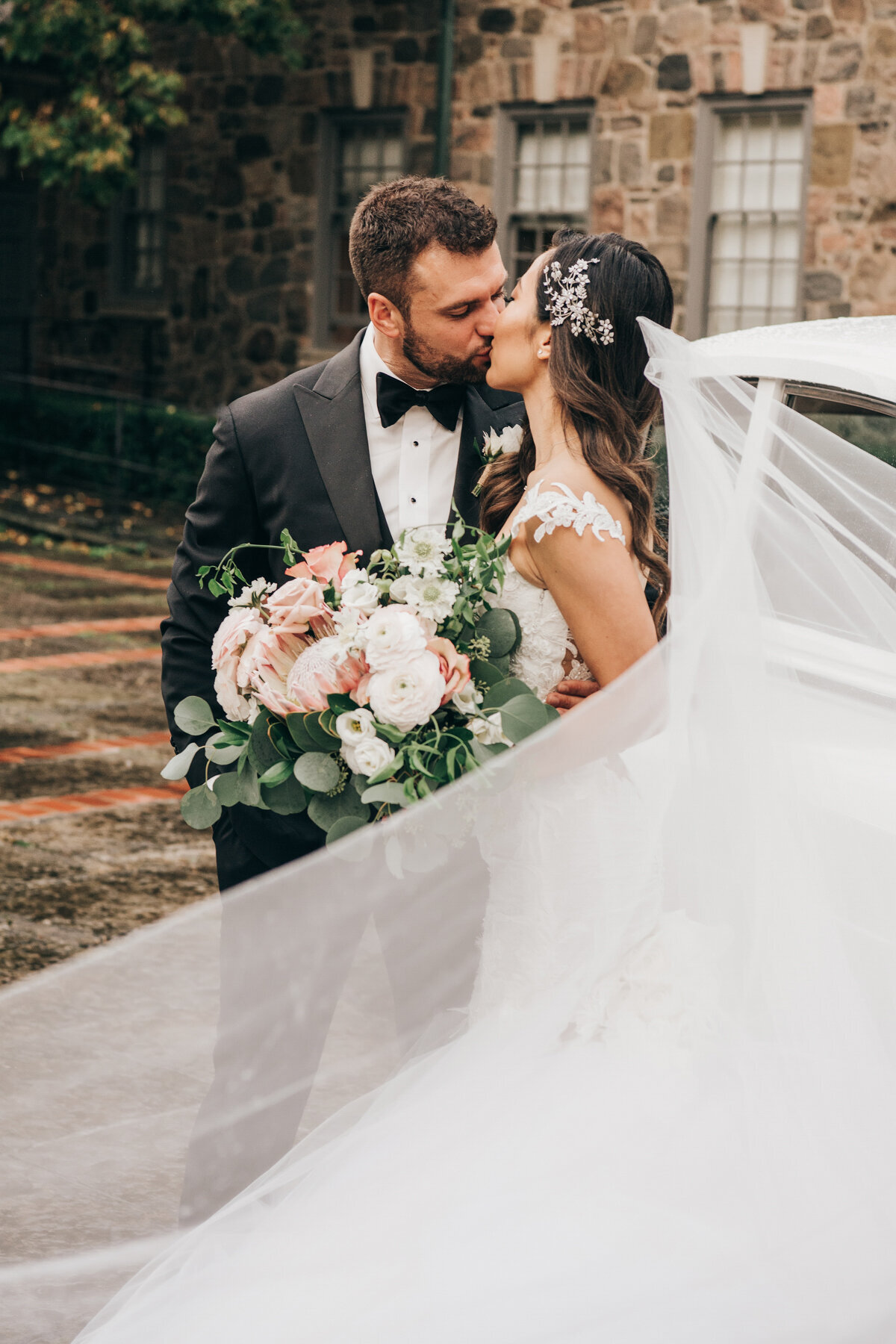 Bride's veil swoops elegantly in front during wedding portraits