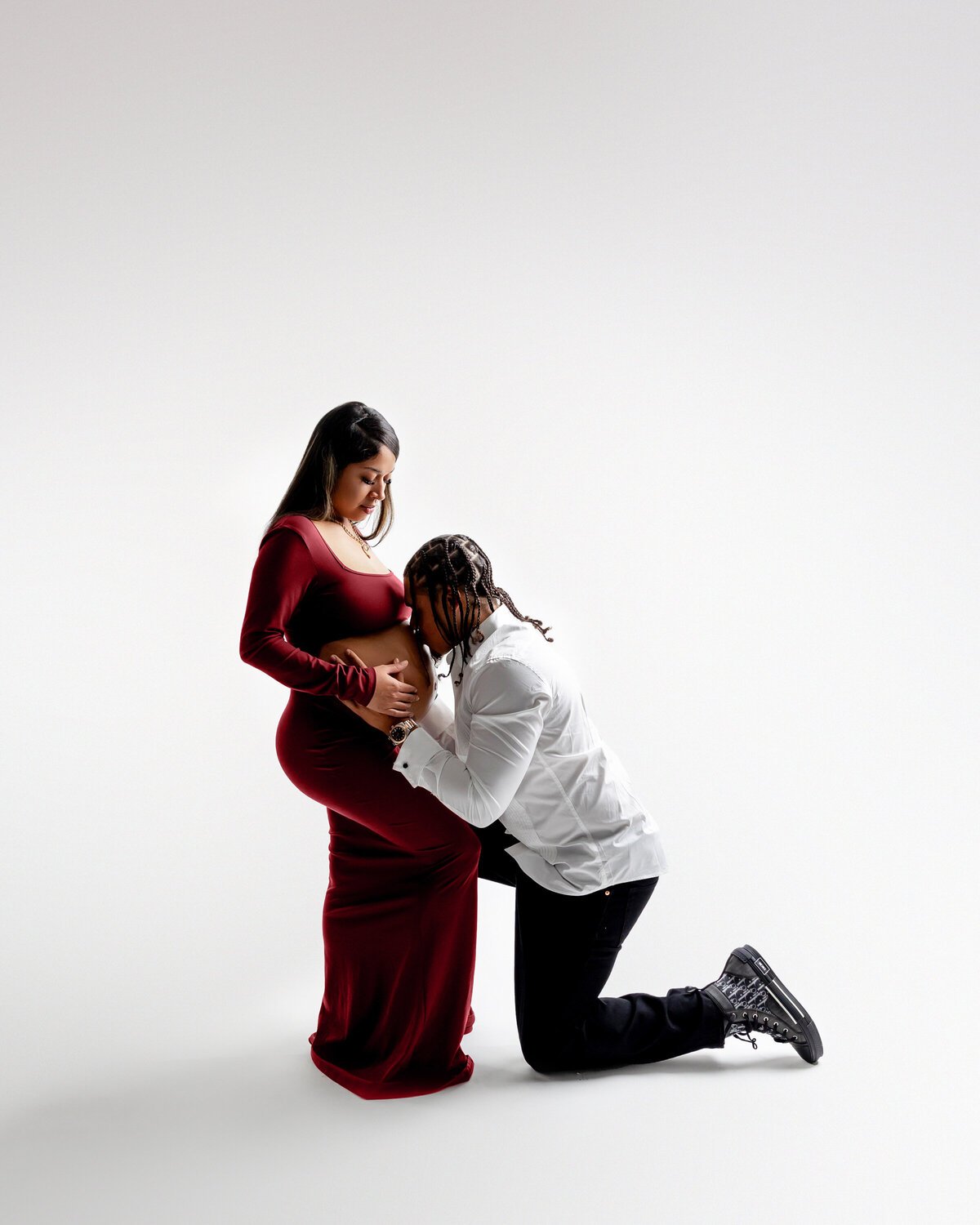 The expectant mother shares a tender moment with her husband as he gently kisses her belly. Captured by Inland Empire photographer Kaitlyn Dawn Photography.