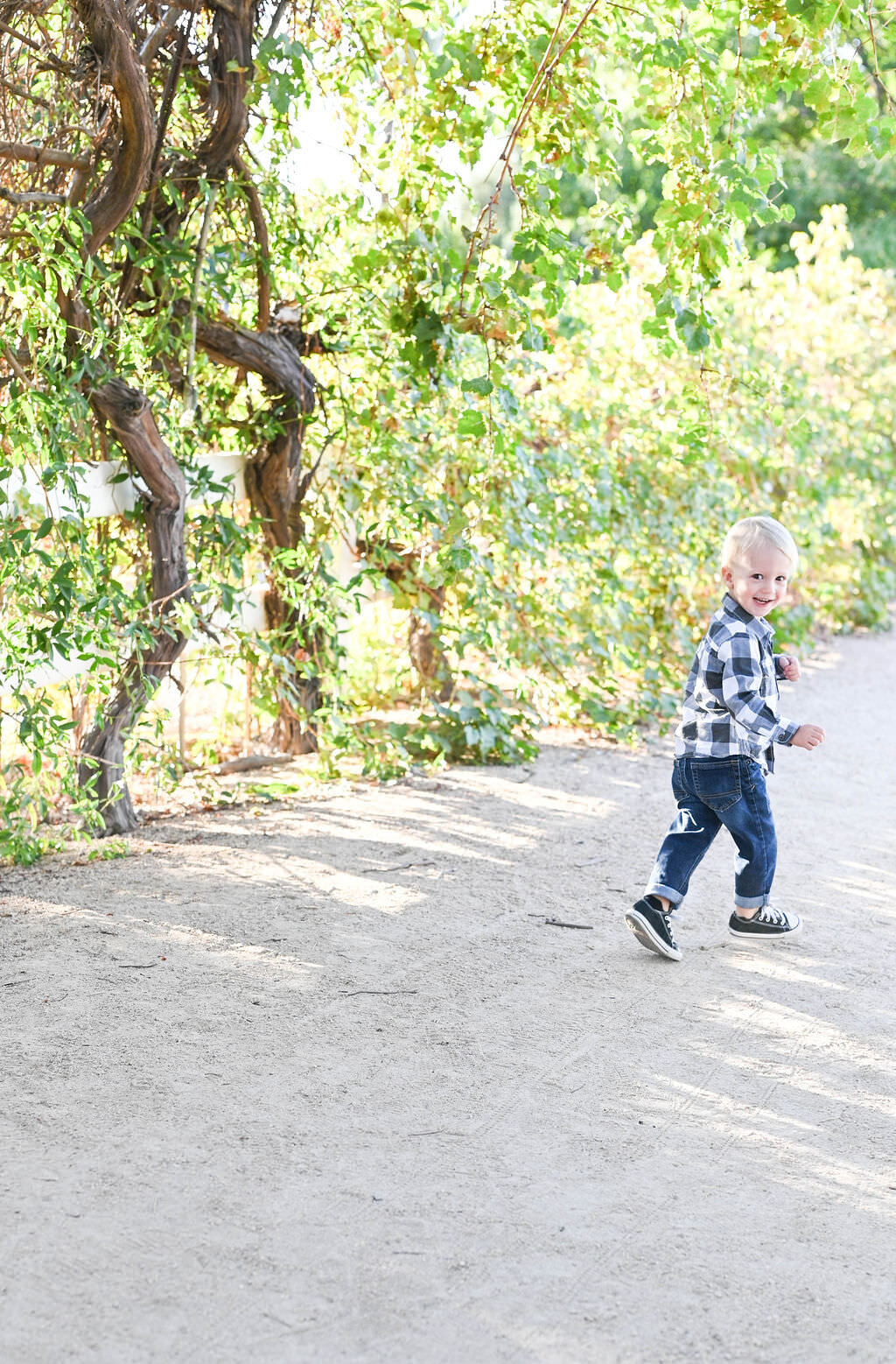A toddler running along a trail in a park.