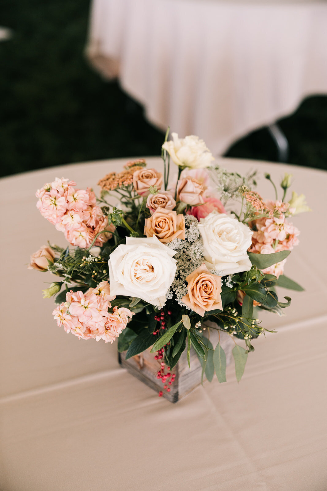 Centerpiece of roses, stock and greenery in aged wooden box