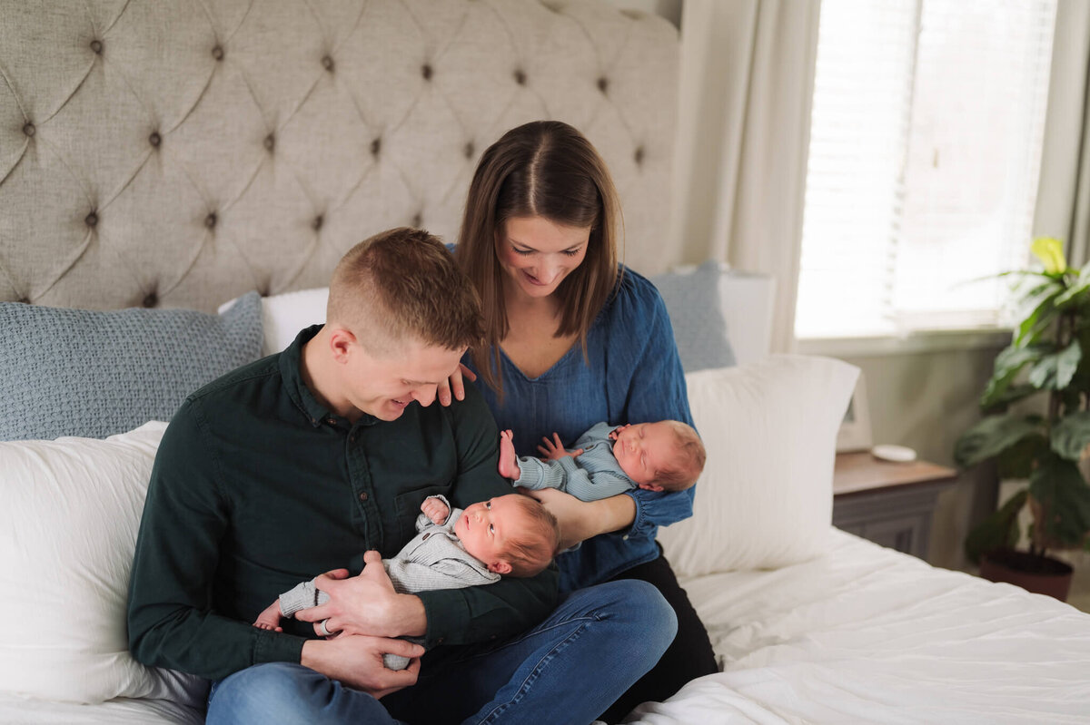 parents holding newborn twins in their home while getting newborn photos taken in their Michigan home