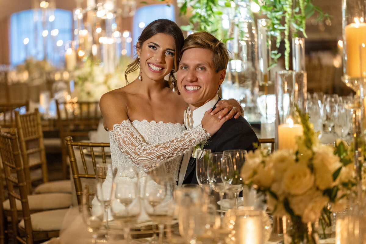 A bride and groom are posing for a picture at their wedding reception.