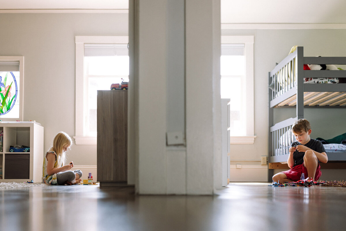 boy and girl sitting on the floor in their own rooms playing with toys with a wall dividing them