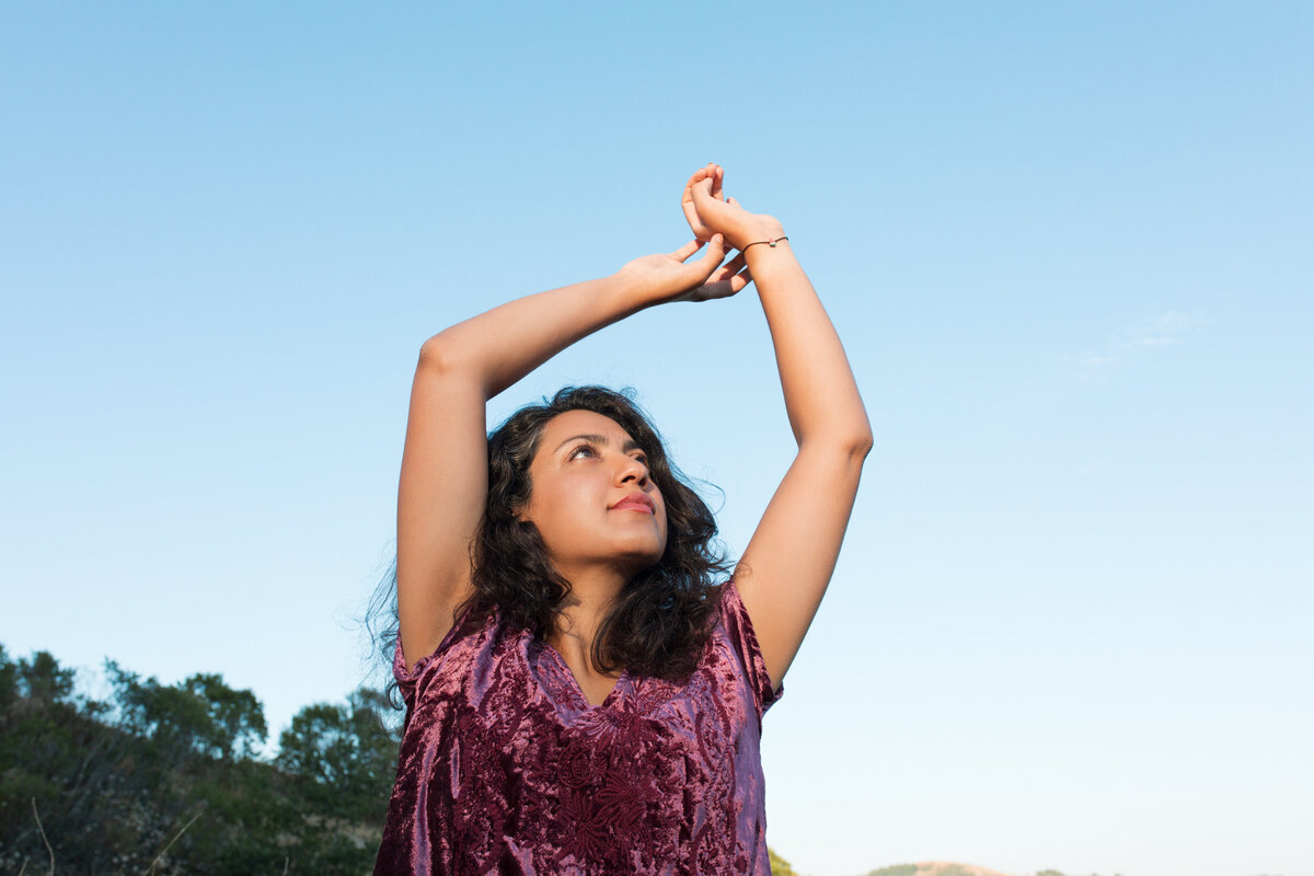 Portrait of woman in a purple dress with hands in the air by Karen Pride