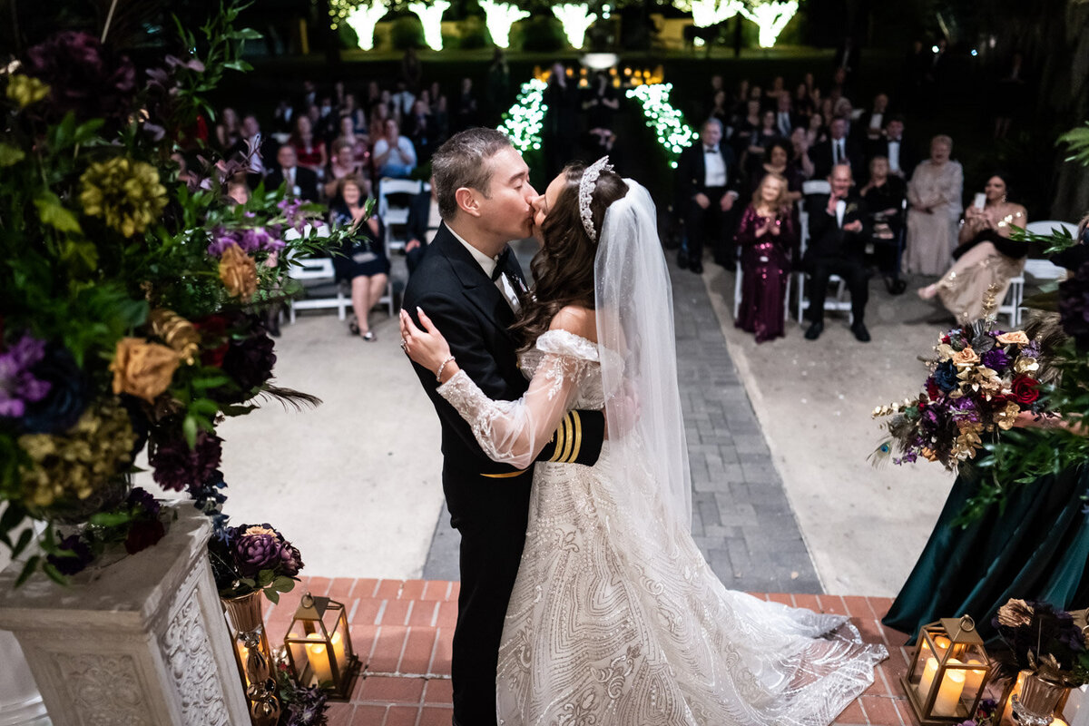 Bride and groom kiss with guests in the background