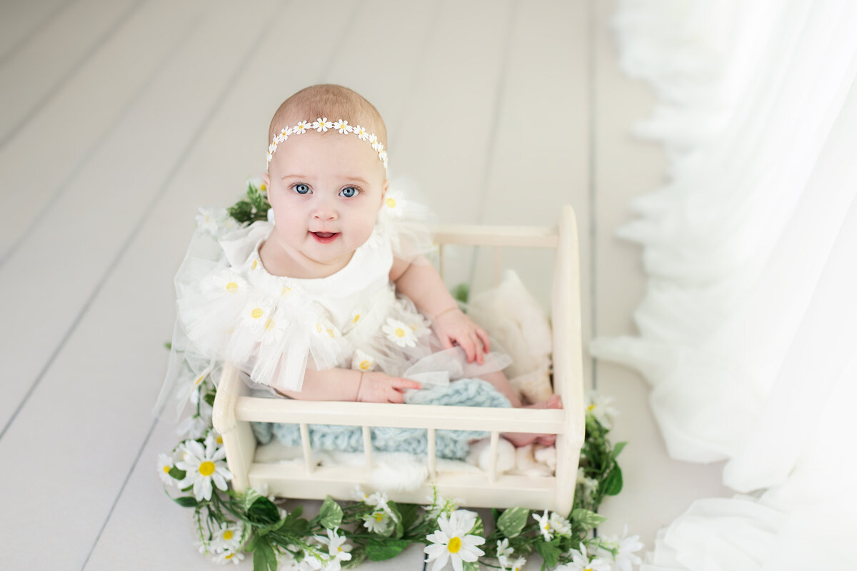  Milestone baby session featuring a daisy-themed look—captured in a soft white studio with floral charm.