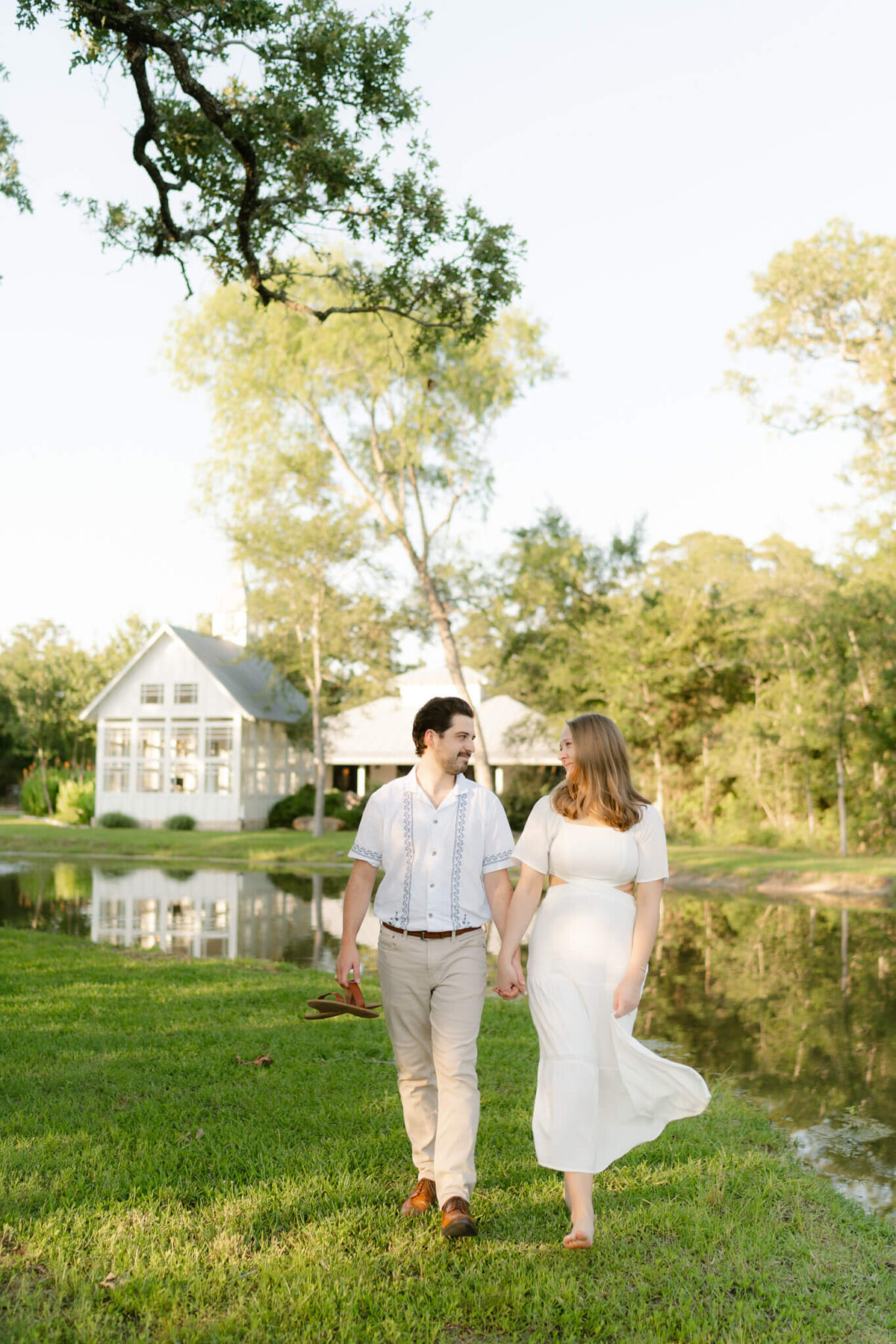 couple holding hands and walking by a pond
