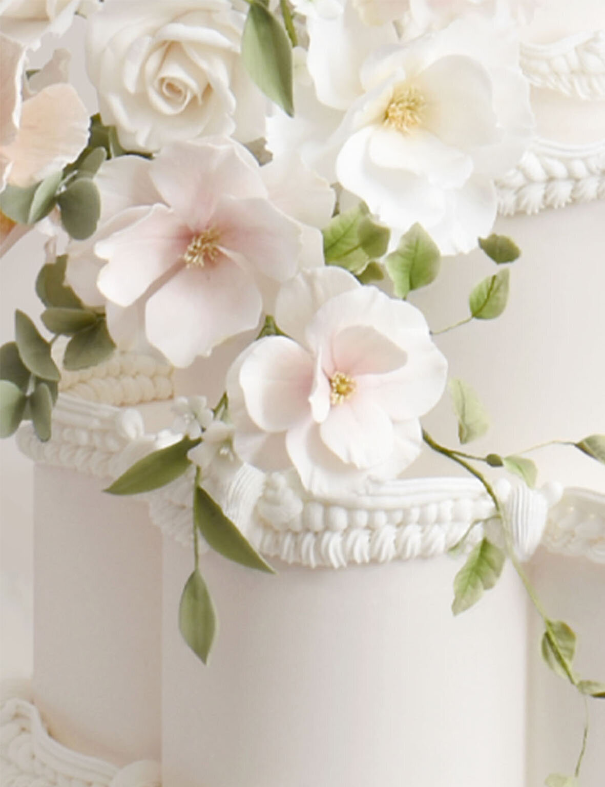 Closeup of a grand white wedding cake with white and pale pink sugar flowers