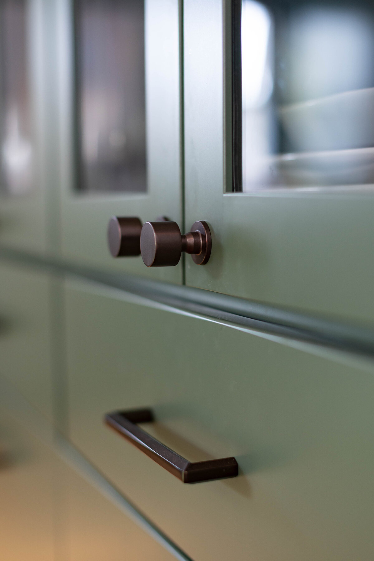 Close up of black hardware on green cabinets