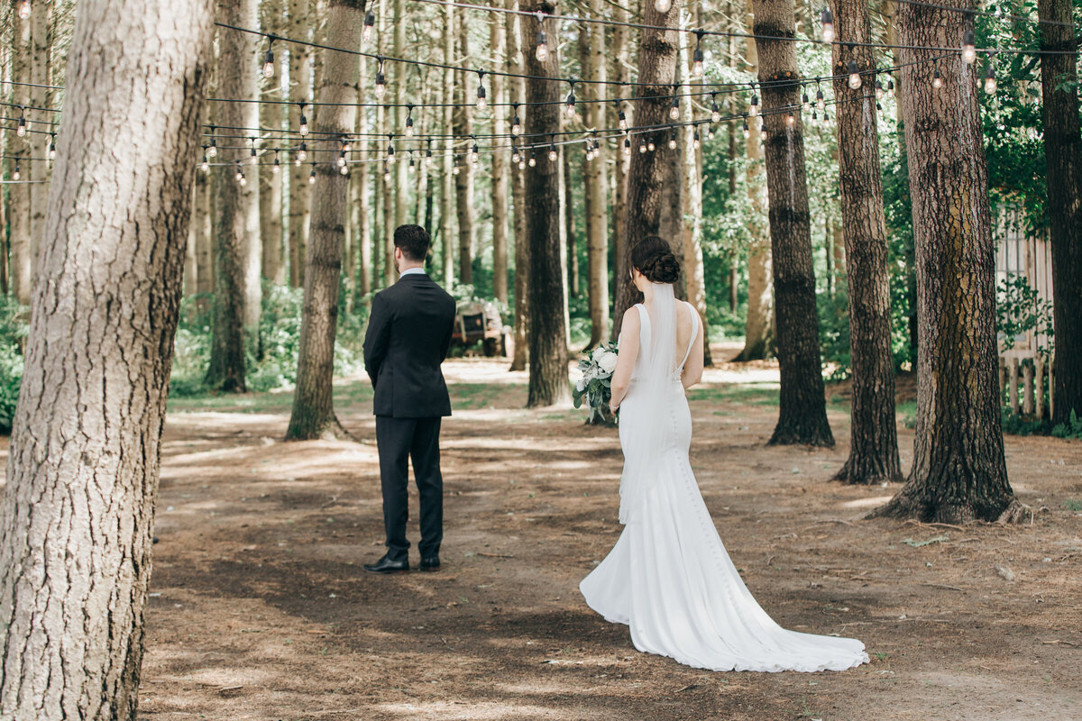 A bride walking up to her groom for a romantic first look in an enchanted forest