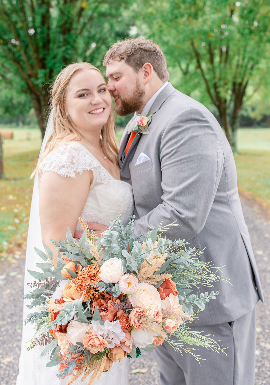 Bride and Groom on a Virginia Country road for wedding portraits holding peach and orange bouquet.