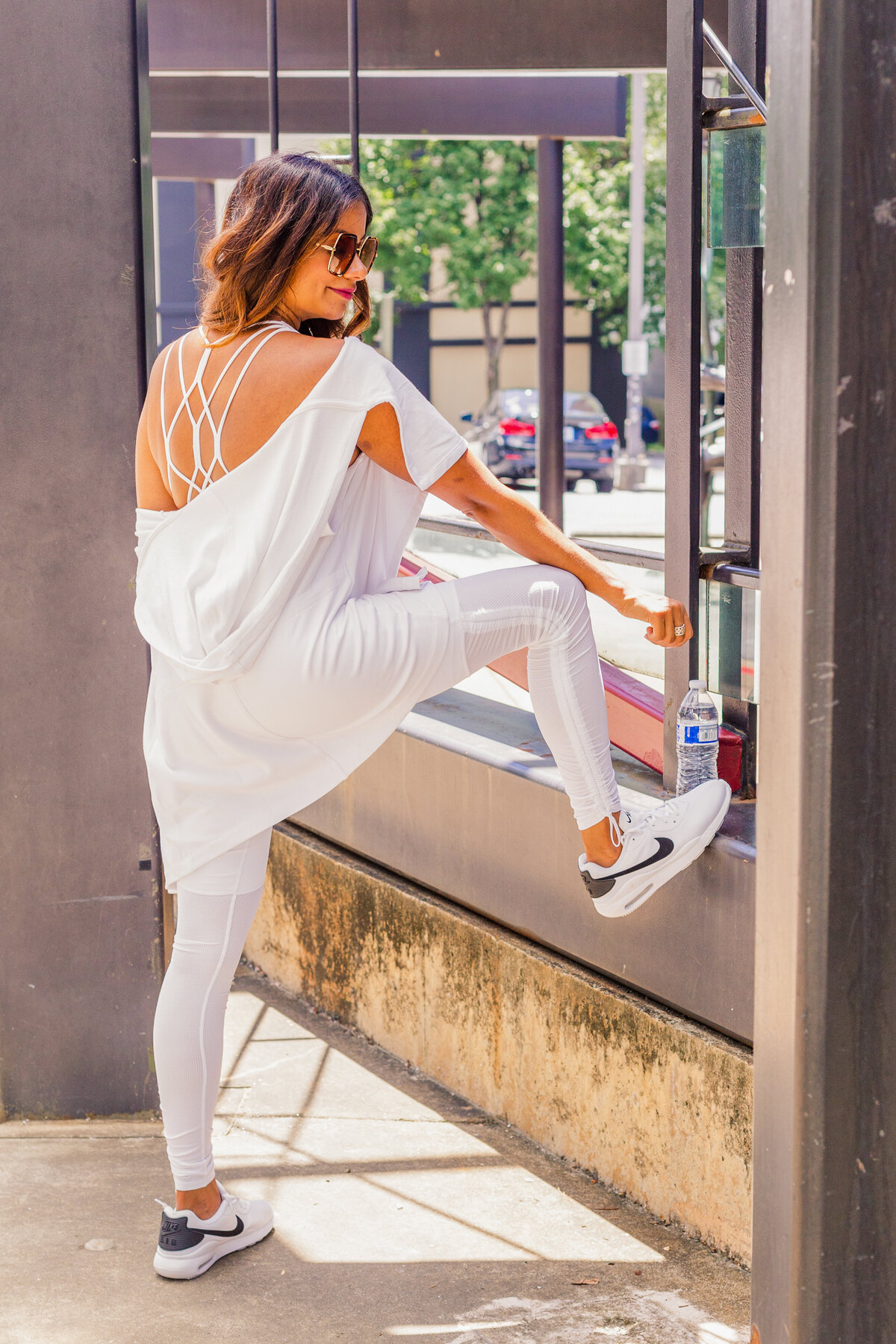woman wearing white athletic  outfit stretching  during photos shoot in Buckhead