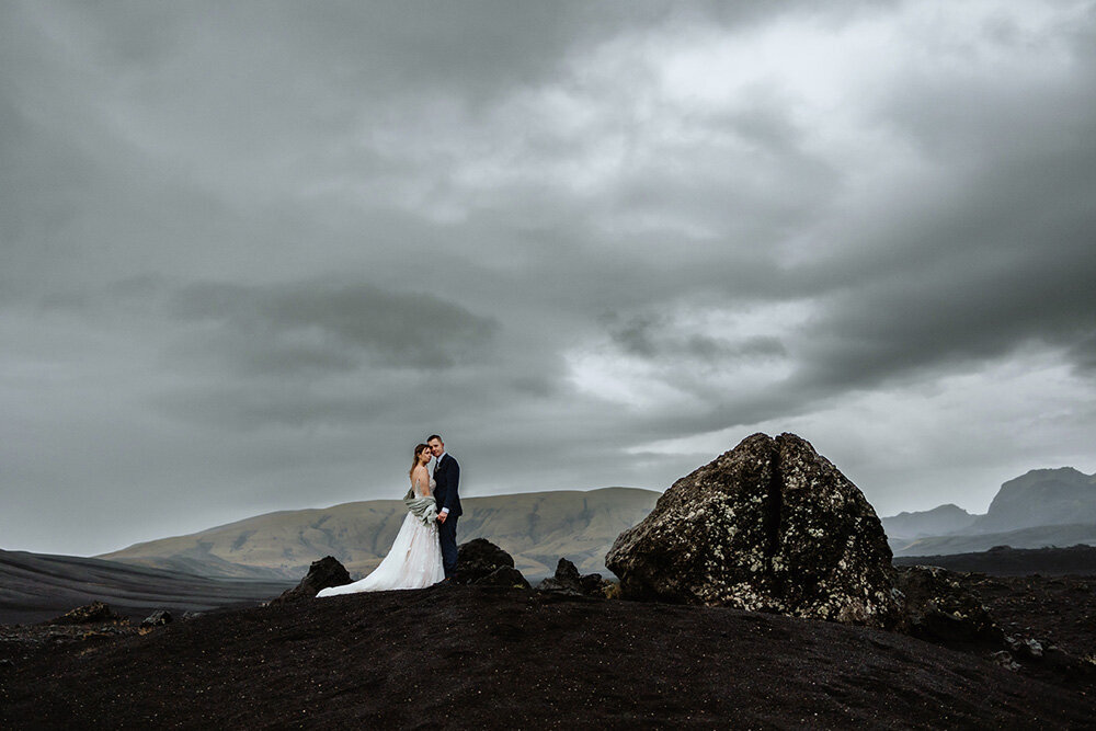 In a whimsical Icelandic meadow, a couple joyfully swings, hand in hand, their wedding day filled with laughter and light-hearted moments.