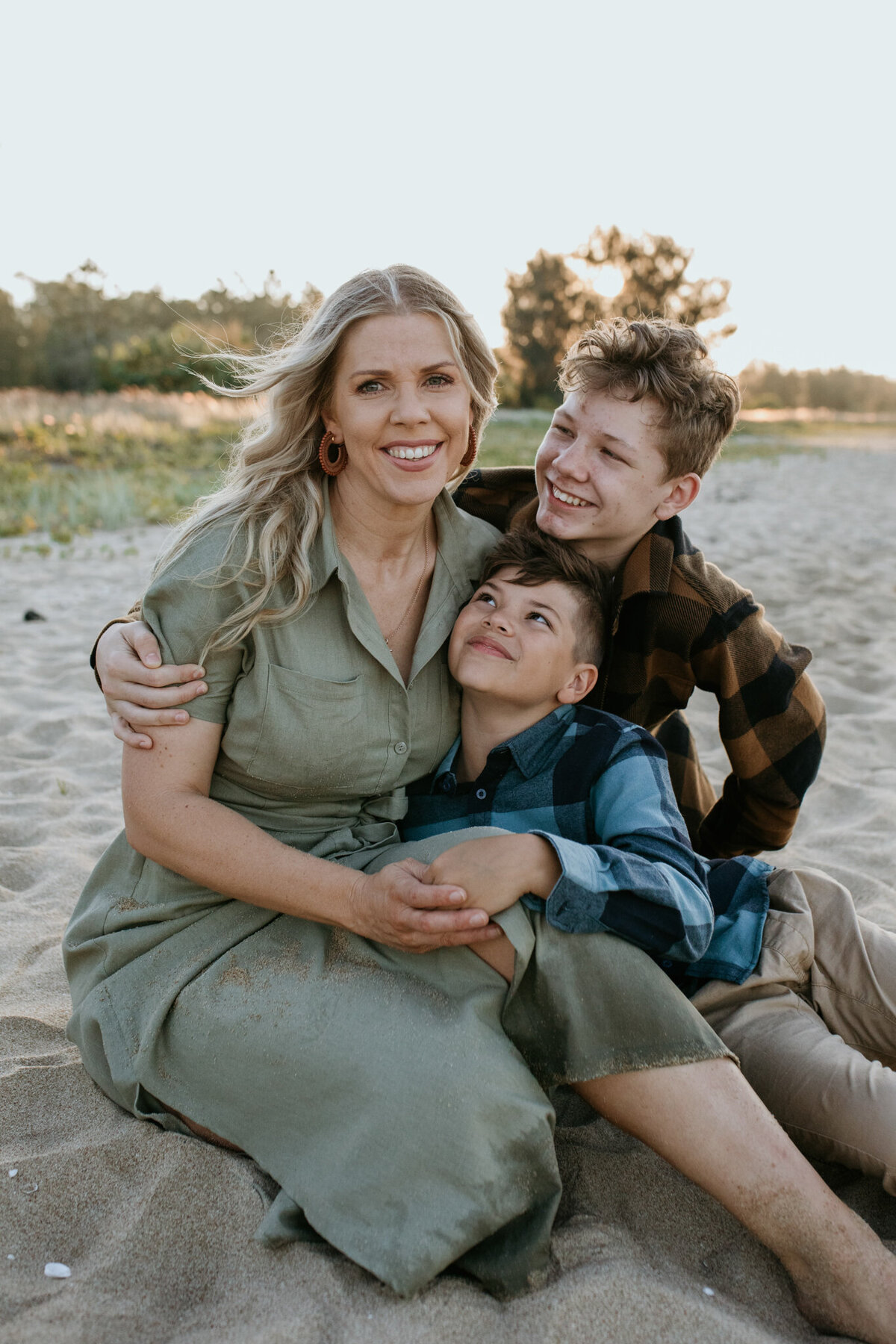 Family portrait of boys looking at Mom on the beach. 