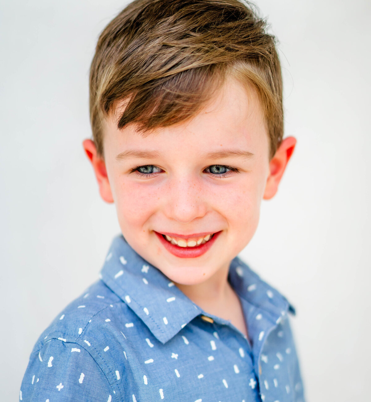 Young boy gazing at camera with genuine expression, white backdrop portrait
