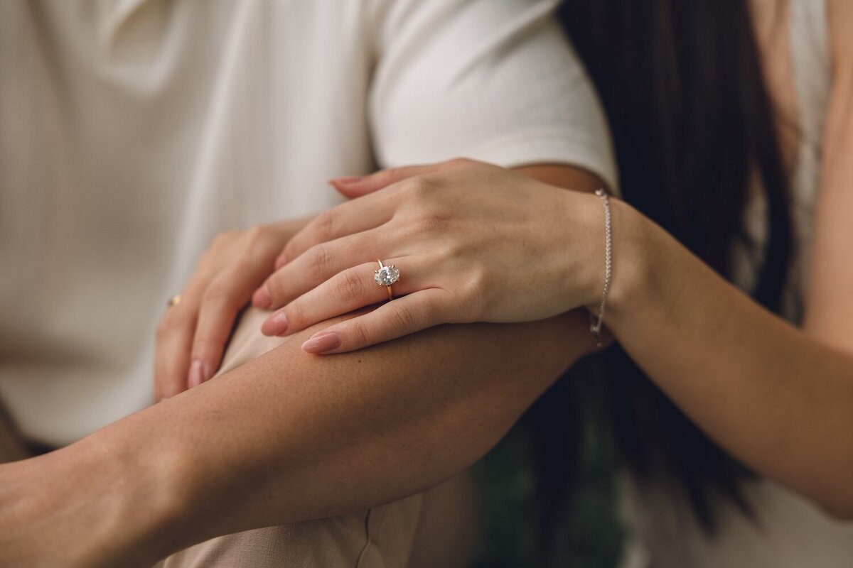Close-up of couple’s hands intertwined, showing engagement ring
