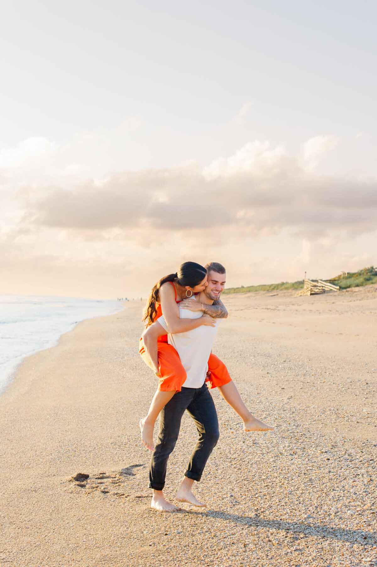 Couple smiling and laughing on the beach while riding piggyback