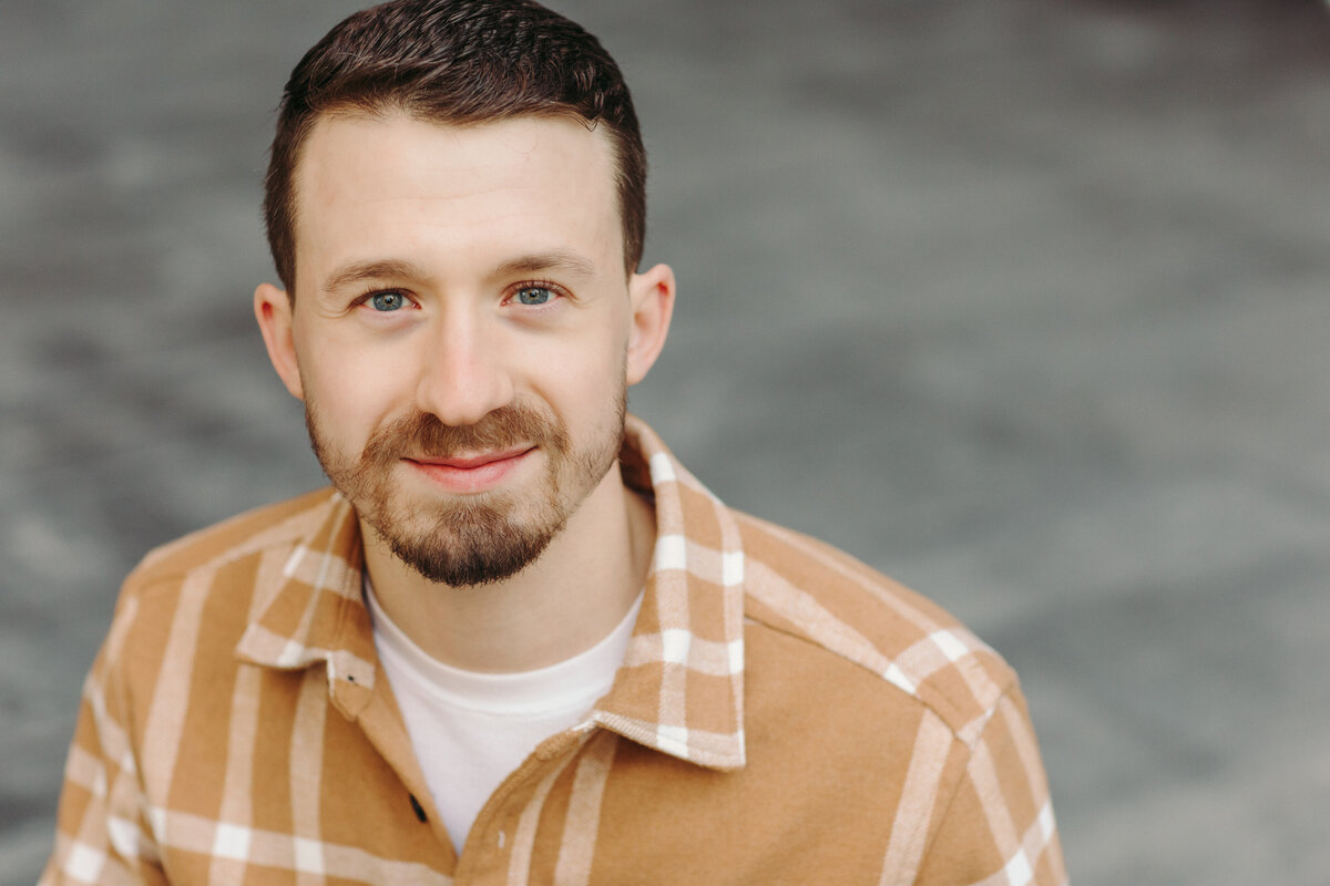 Utah Family Photographer captures man in headshots smiling wearing plaid shirt