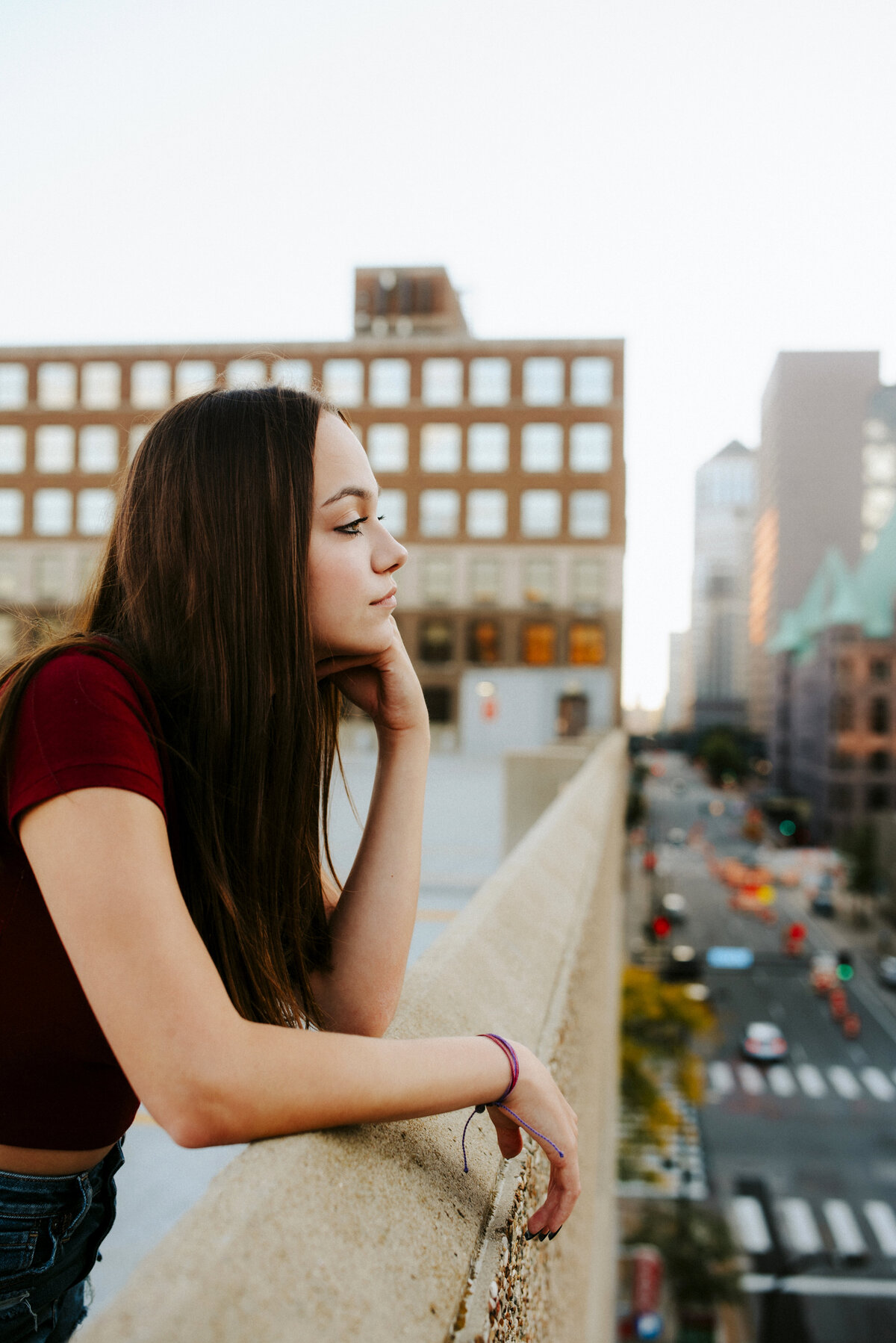 Capture the essence of urban senior portraits in downtown Minneapolis as our model strikes a pose on top of a parking garage, with the city streets below providing a stunning backdrop.