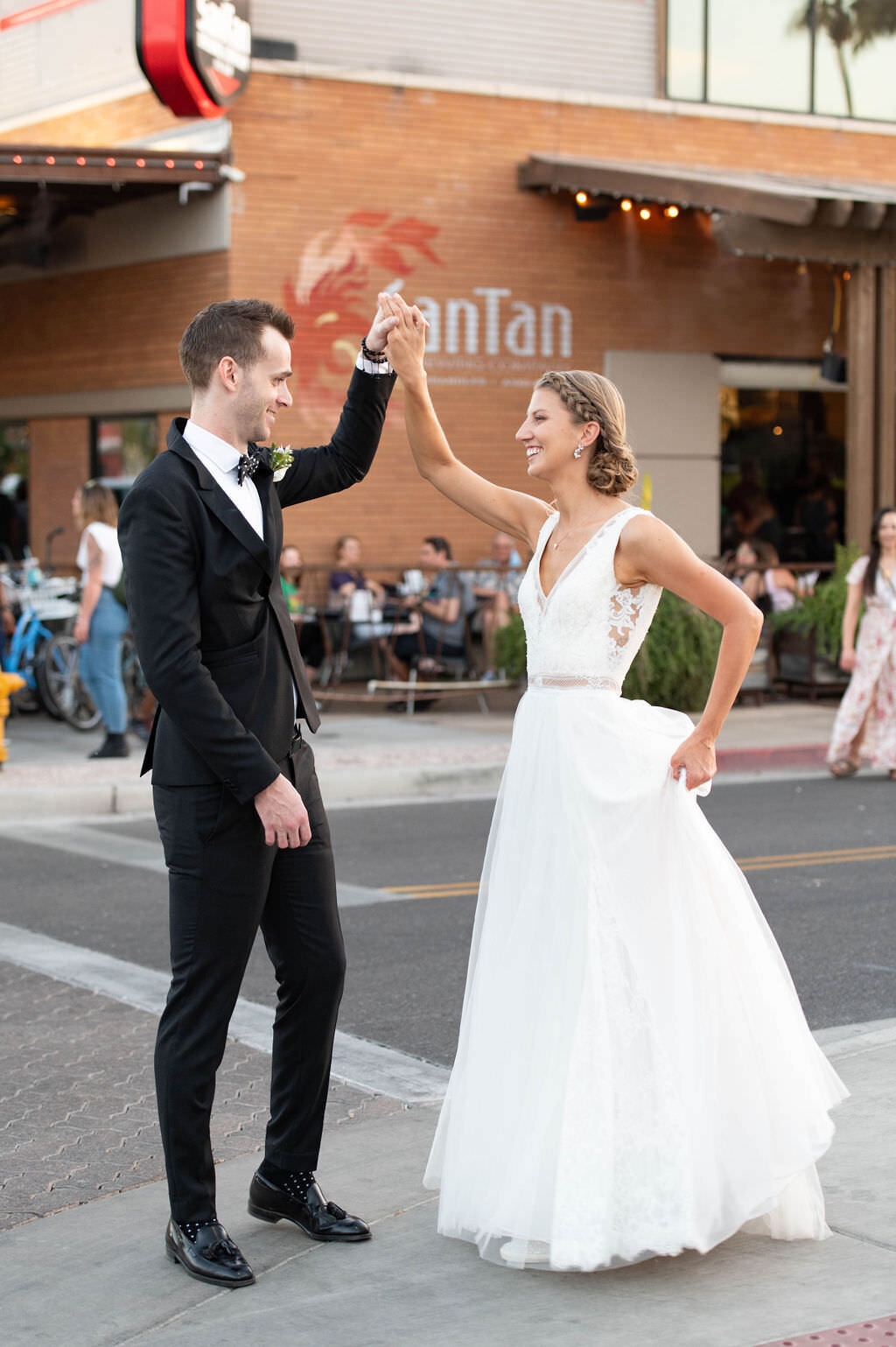 A bride and groom dancing together on a sidewalk.