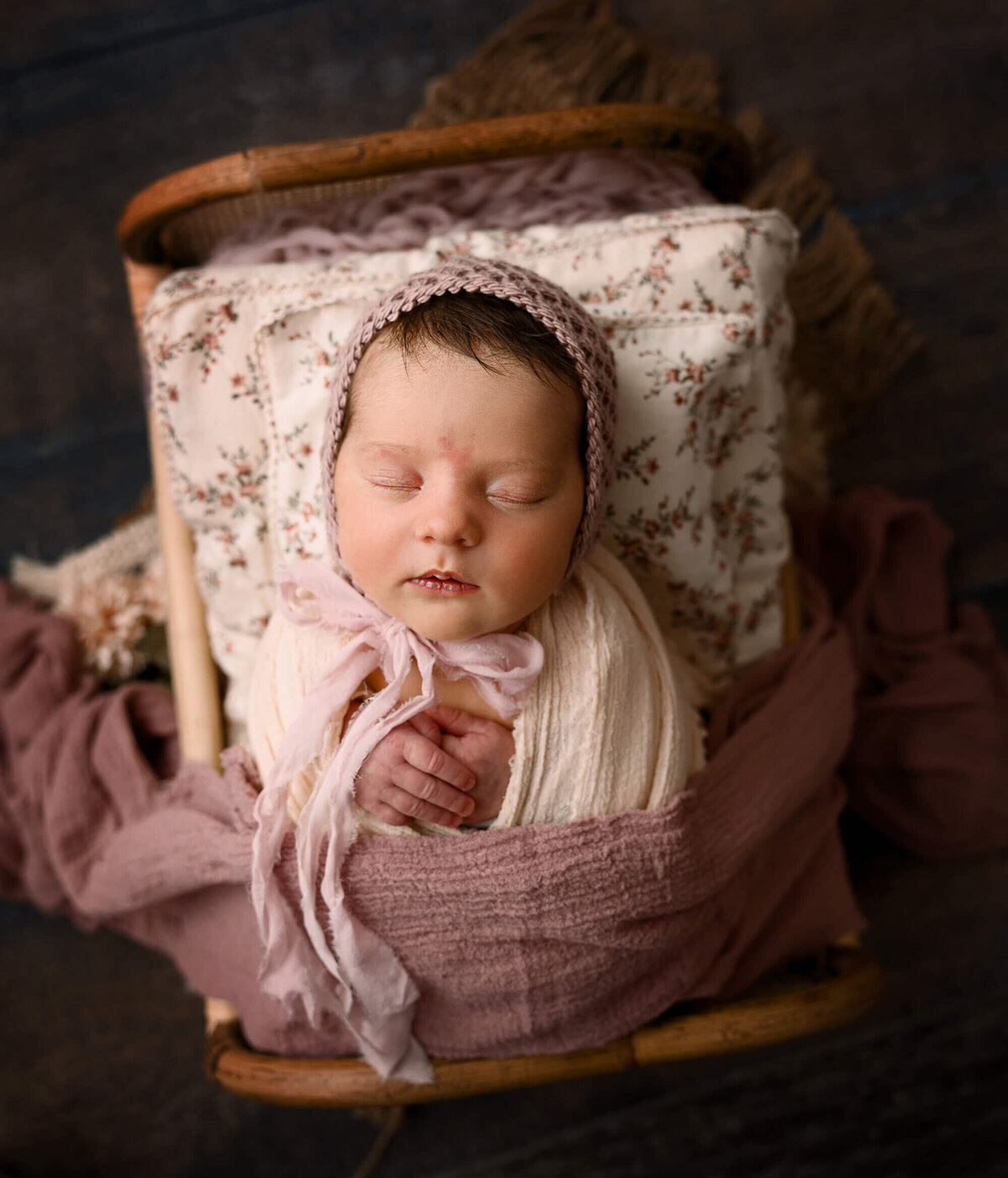 Newborn girl with bonnet in a bed