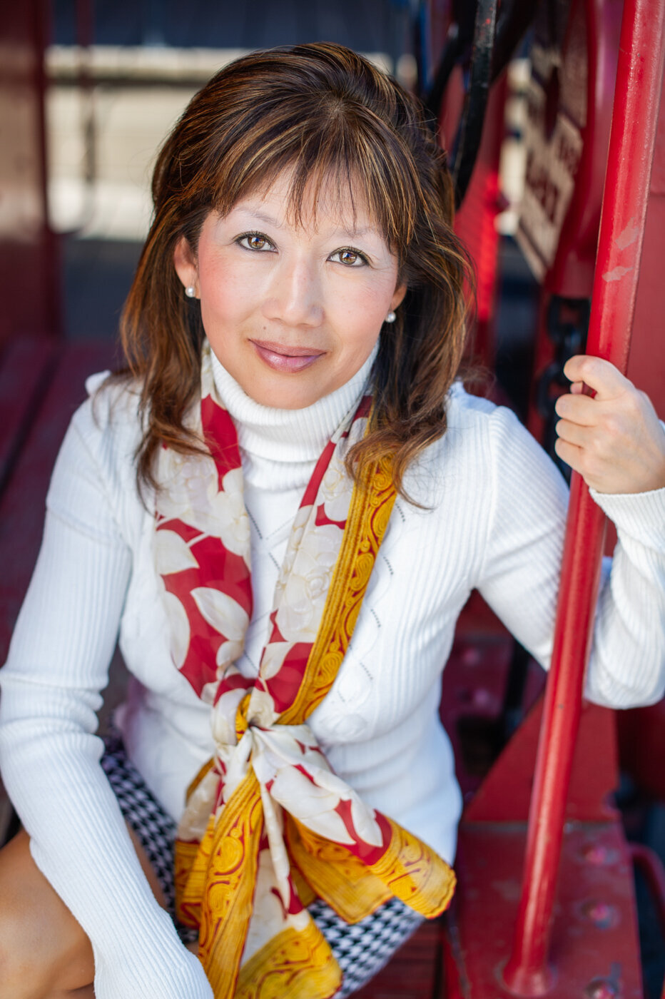 Professional Headshot of an Asian travel agent posed by a red train caboose in San Juan Capistrano, CA.