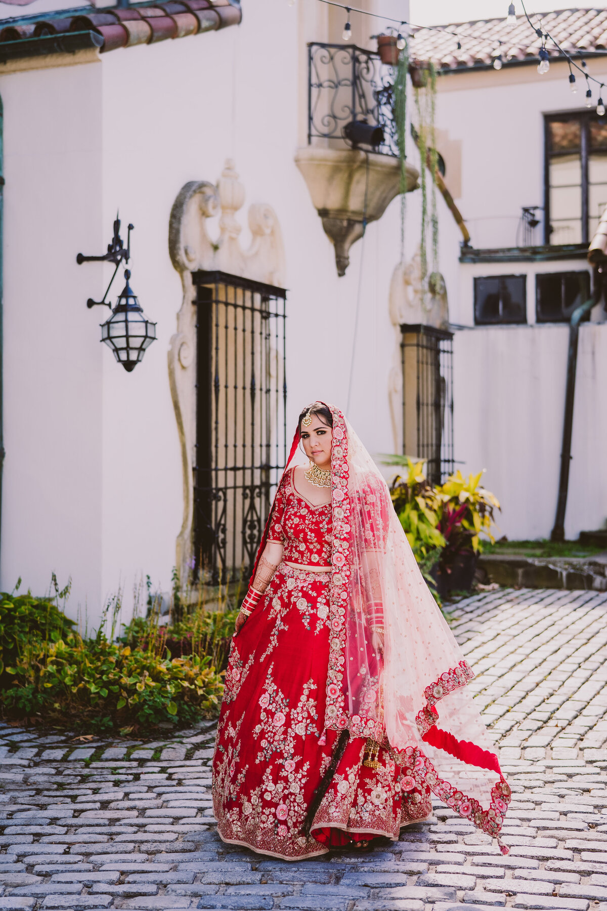 Indian bride in a red lehnga posing for the camera at the vanderbilt museum 