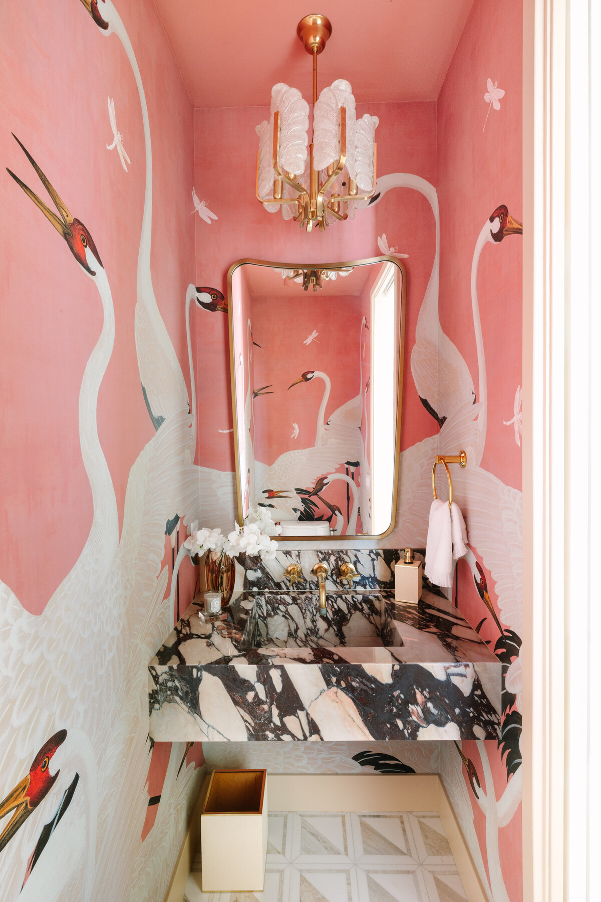Small space powder room with Calacatta Vagli vanity and sink, Gucci Heron wallpaper, Italian shield mirror, and vintage Carl Fagerlund for Orrefors 1960's pendant.