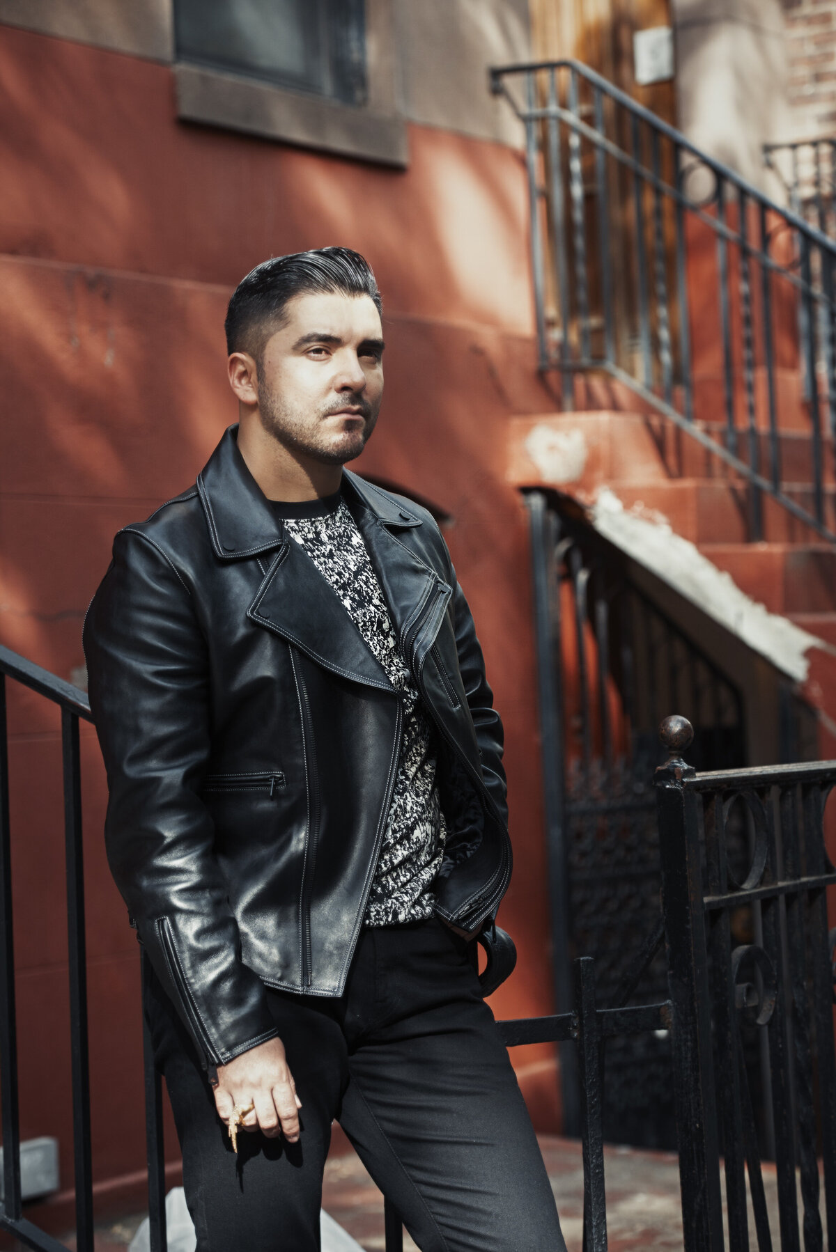 A person in a leather jacket standing outside of an apartment building