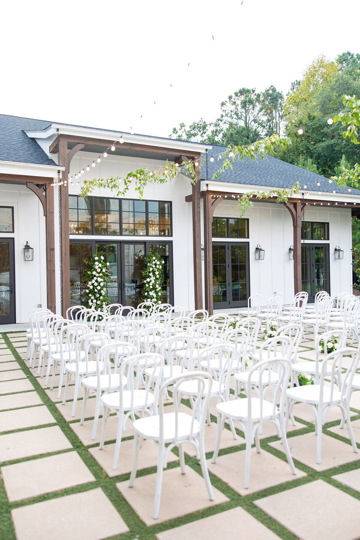 White chars neatly lining an elegant outdoor wedding ceremony space