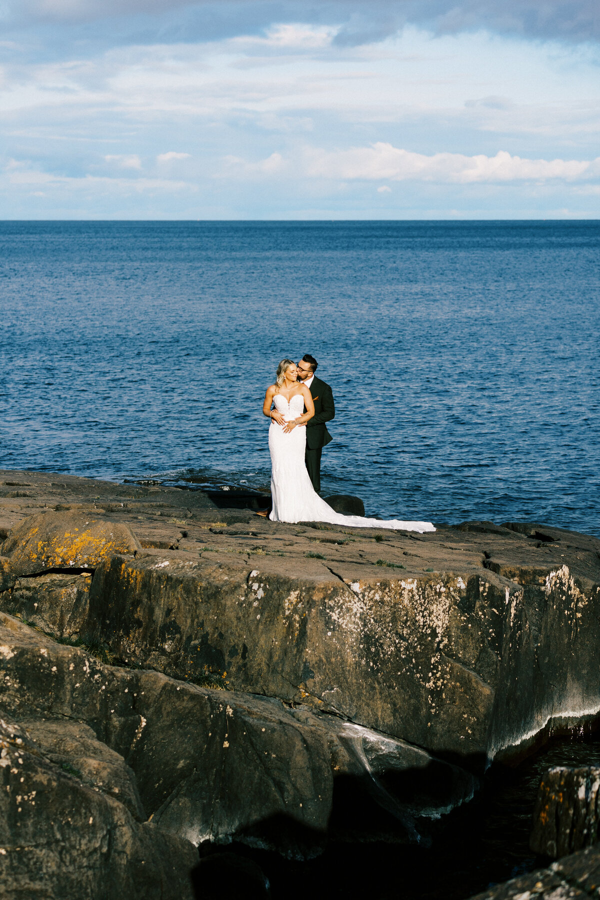 newlyweds embracing on the rock of Lake Superior  in Duluth