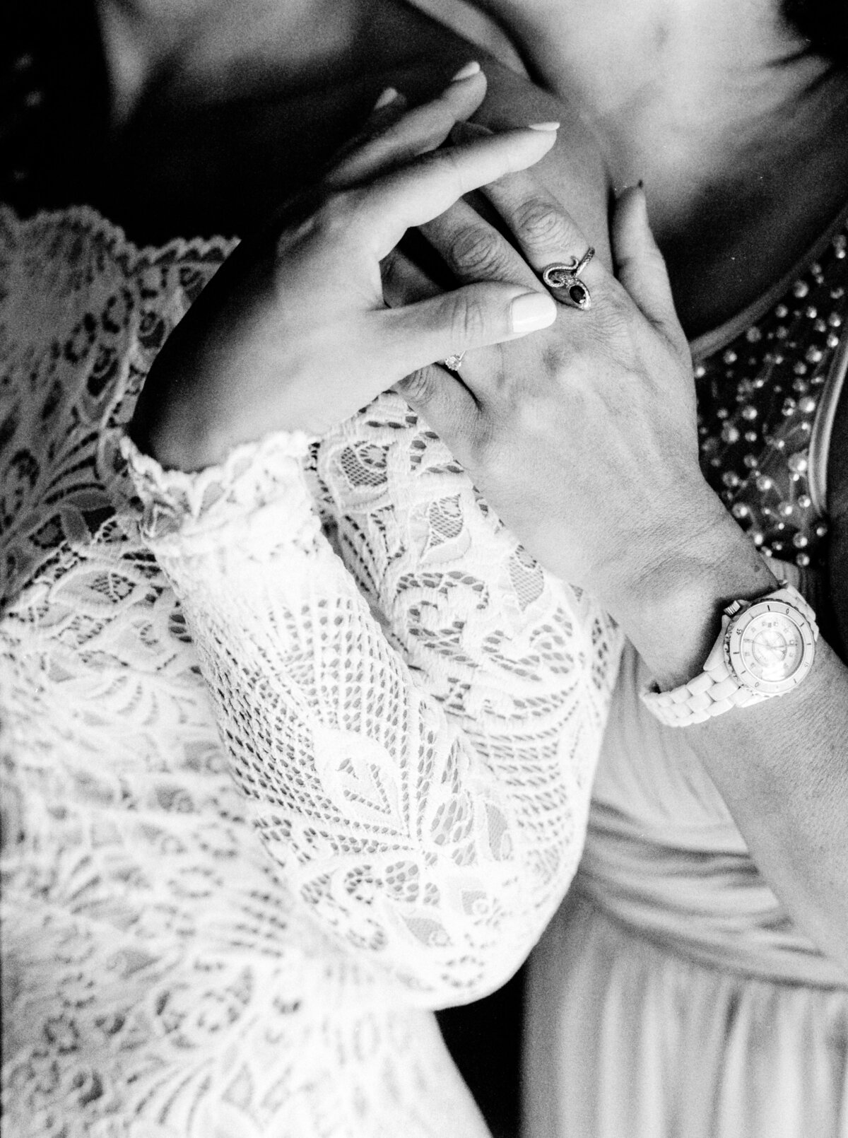 Black and white film photograph of a mother of the bride and brides hands overlapping on one another photographed by Italy wedding photographer at Villa Montanare Tuscany wedding