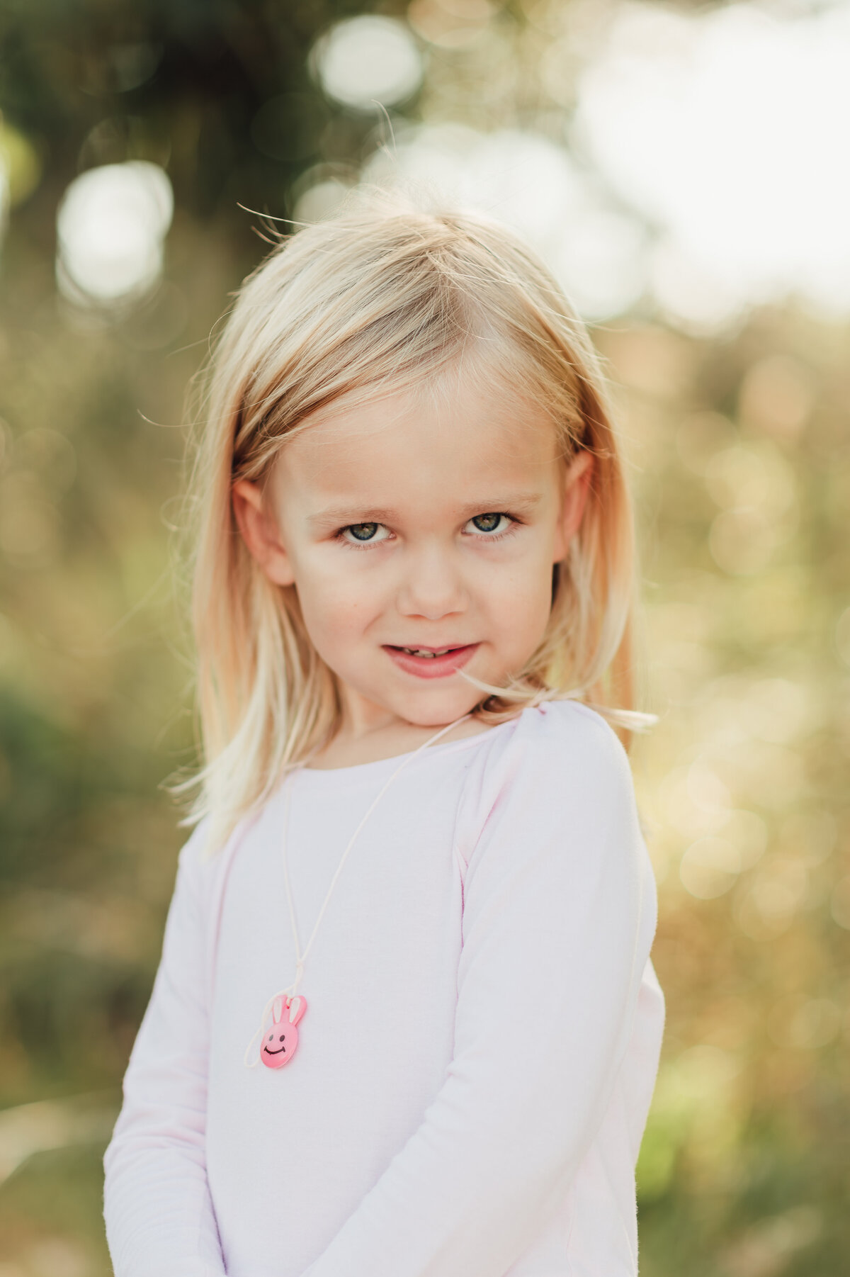 A student standing in a sunlit field during an outdoor school portrait session, capturing natural charm.