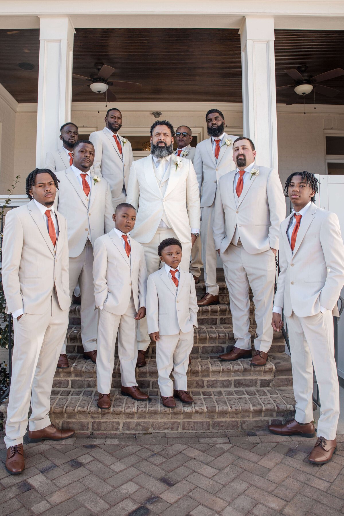 A sharply dressed groom stands with his groomsmen, all wearing coordinated white suits.