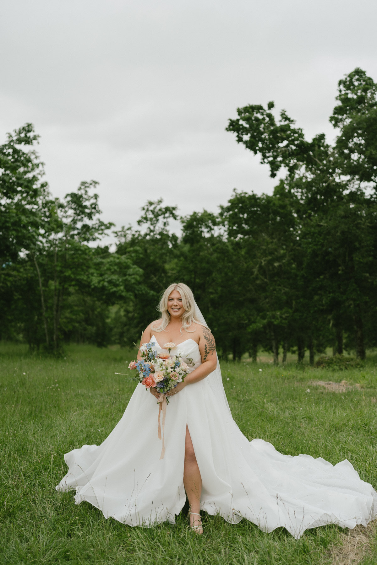 A bride standing outdoors with flowers, representing bridal makeup done by Looks with Libby.