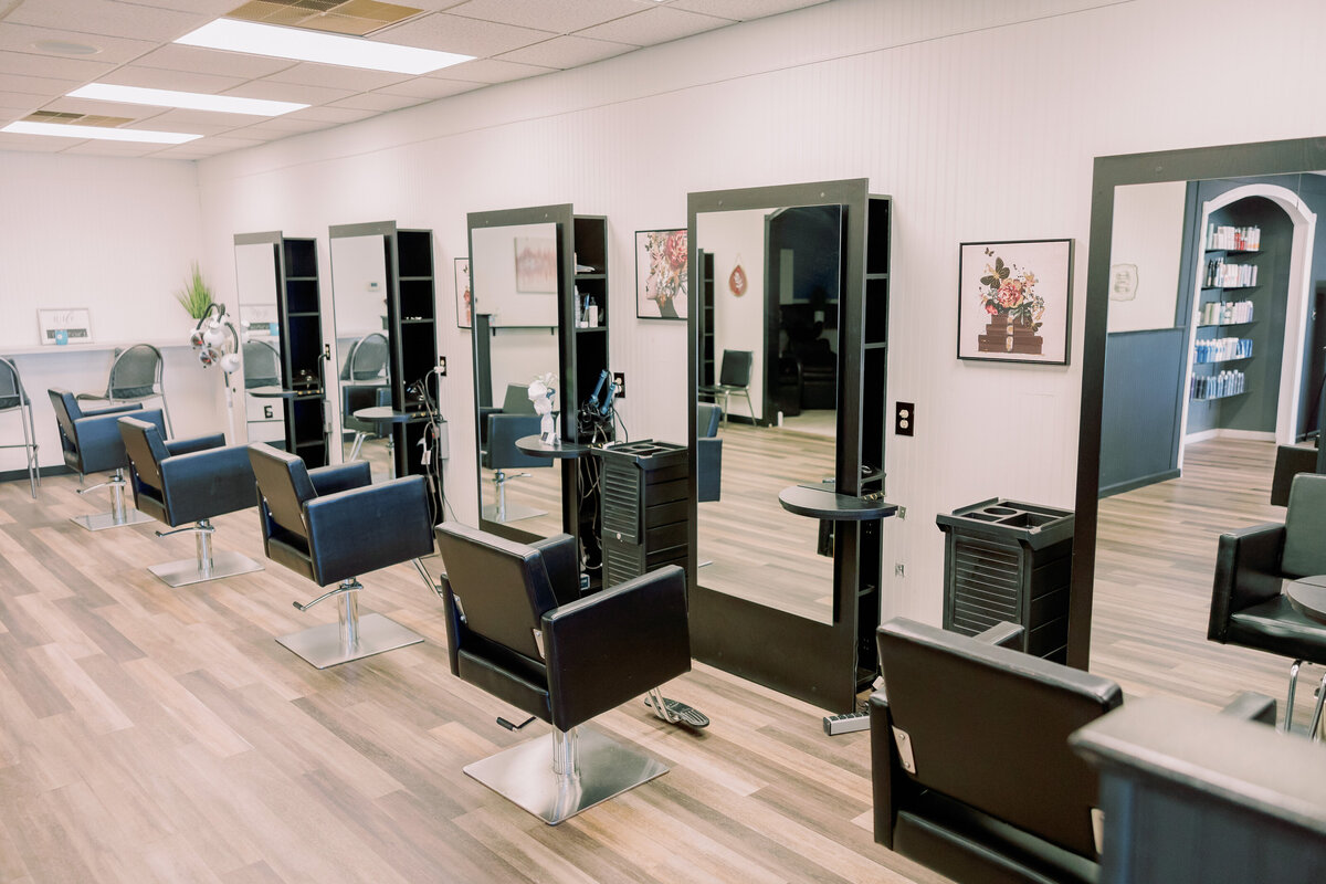 Empty salon chairs sit in front of mirrors.