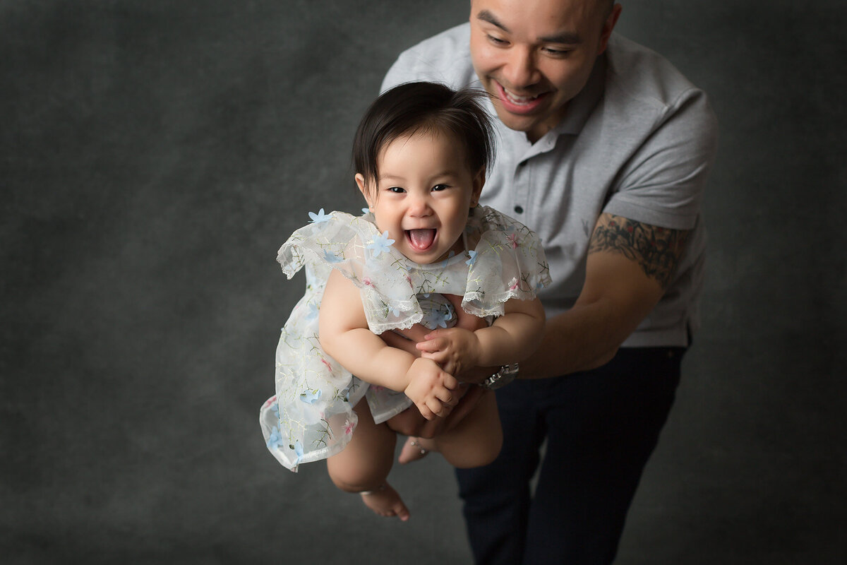 A joyful interaction between a dad and his toddler daughter captured by a Dallas family photographer, showcasing their playful bond.
