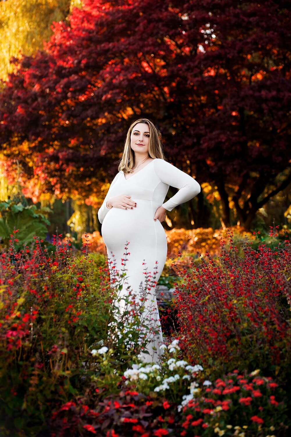 38 week expecting mom in white Chicaboo Grace maternity gown surrounded by flowers at Deer Lake Park