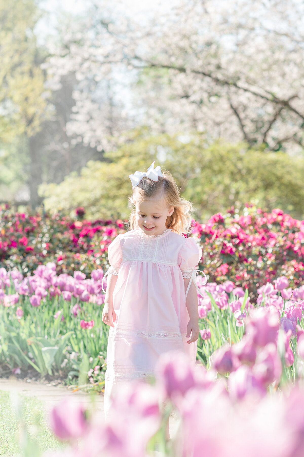 Young blonde girl delightfully smiling in a field of tulips.